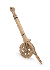 An antique carved whalebone jagging wheel pie crimper with carved fist finial, 18th/19th century, 18.5cm long.