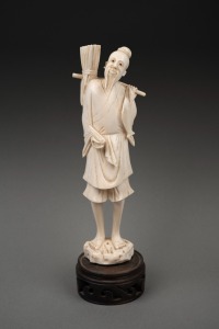 A vintage Chinese carved ivory statue of a fisherman, standing on a turned timber base, early to mid 20th century, 22cm high overall.