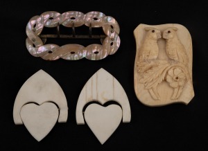 An antique mother of pearl belt buckle, a beautifully carved ivory pot lid decorated with cockatoos with garnet eyes, and a pair of carved whalebone sweetheart trinkets, 19th century, the buckle 6.5cm high.
