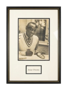 1936 BERLIN: JESSE OWENS: Signed photograph of Owens displaying three of his four Olympic gold medals, framed and glazed, 43.5 x 30.5cm overall.