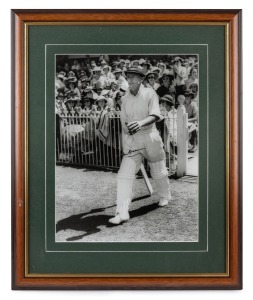 DON BRADMAN: Framed and glazed photograph print of Bradman stepping out to bat at the MCG, featuring Bradman's original signature in permanent marker; 60 x 50cm overall.