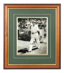 DON BRADMAN: Framed and glazed photograph print of Bradman stepping out to bat at the MCG, featuring Bradman's original signature in permanent marker; 45 x 39cm overall.