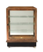 An antique Tasmanian oak and copper bound shop display cabinet with four large drawers and unusual slimline display case front, circa 1900, electrified and on later casters, 104cm high, 77cm wide, 62cm deep.