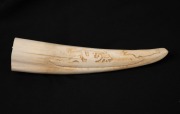 An Inuit carved walrus tusk with carved seal hunting scene, ​​​​​​​17cm long.