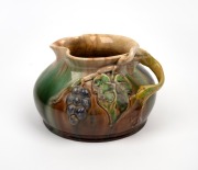 REMUED pottery jug with applied grapes and branch handle, incised "Remued Hand Made 173 LM", ​​​​​​​11cm high, 18cm wide.