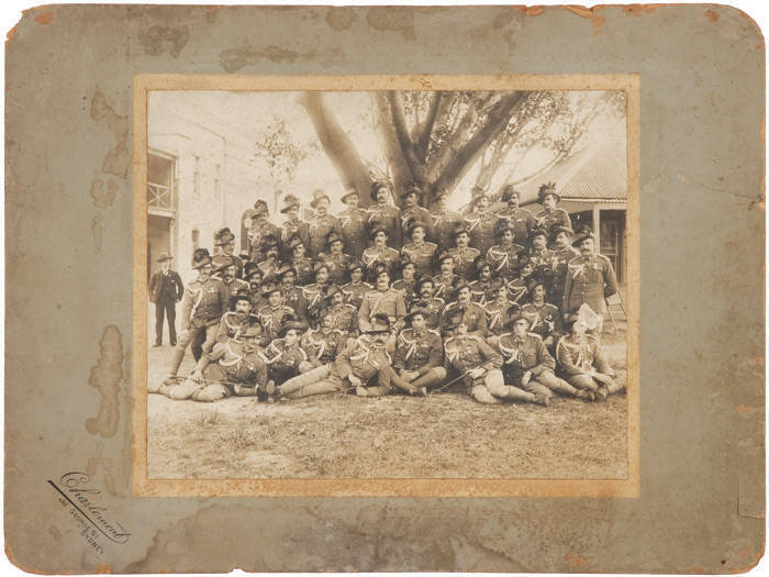 c1890-1900 [AUSTRALIAN SOLDIERS IN FULL DRESS UNIFORM], toned silver gelatin photograph, with printed studio line "Charlemont, 492 George St, Sydney" laid down on original backing, 23.3x28.9cm. [Some surface loss affecting the soldier in 1st row, lower ri