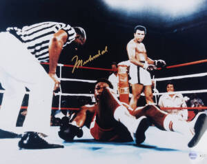 MUHAMMAD ALI, signed colour photograph of Ali standing over George Foreman, size 51x41cm. With 'Online Authentics' No.9679.