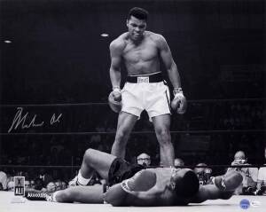 MUHAMMAD ALI, signed b/w photograph of Ali standing over Sonny Liston, size 51x41cm. With 'Online Authentics' No.OA-8090301.