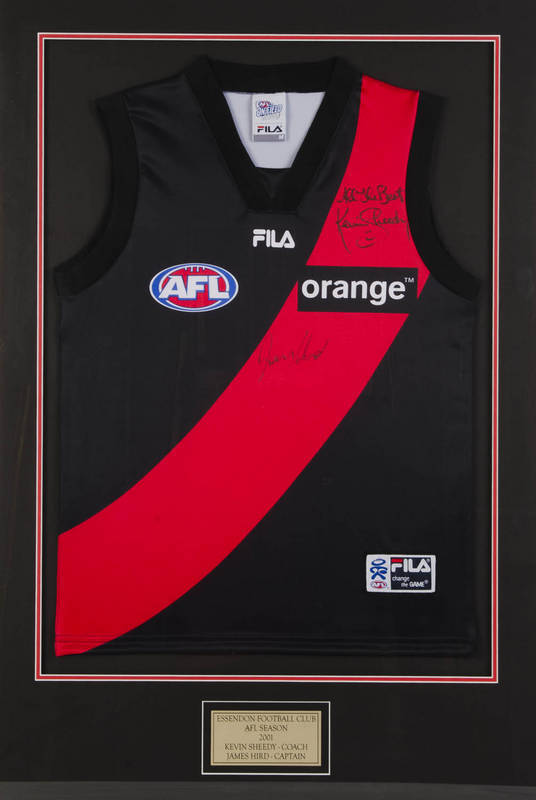 ESSENDON: Essendon 2001 jumper signed by Kevin Sheedy (coach) & James Hird (captain), window mounted, framed & glazed, overall 73x105cm.