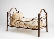 An antique wrought iron dolls cot with embroidered cushions, height  35cm, width 45cm, depth 25cm. 