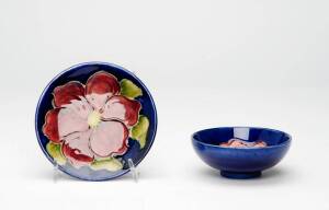 MOORCROFT: Two floral patterned dishes on blue background, mid 20th century. 9.5cm & 11.5cm.