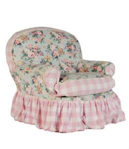 An upholstered armchair covered in pink and floral pattern fabric
