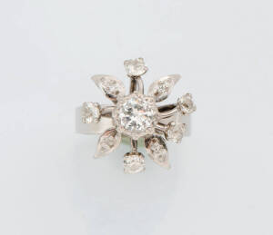A diamond floral cluster ring.The central transition cut diamond surrounded by old and single cut diamonds. Size M&frac12;. 18ct white gold.