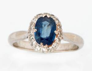 A sapphire and diamond cluster ring. The oval sapphire surrounded by single cut diamonds. Size P&frac12;. 18k white gold.