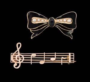 Two Australian brooches. An enamel bow by Willis and a gold musical brooch by Lawrence.