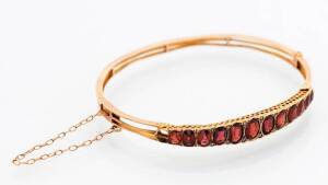An Edwardian garnet bangle. 9ct yellow gold. Weight 8 grams.