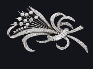 A diamond spray brooch. The stylised spray set with round brilliant and baguette diamonds. 18ct white gold.&nbsp;