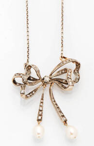 An antique diamond and pearl bow pendant on chain. Yellow gold and silver.&nbsp;