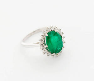 An emerald and diamond dress ring. The oval emerald T.C.W 3.04ct surrounded by small brilliant diamonds T.C.W .28ct. White gold.&nbsp;