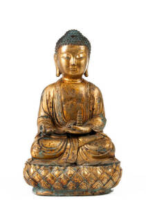 A very heavy cast gilt bronze Buddha, seated on a lotus base, holding a pagoda in one hand, 34cm high
