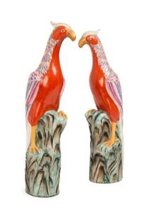 A large pair of Fencai enamel phoenix, 20th century, each one perched on a large rock, the elaborate plumage in red, yellow & blue enamel with gilt, the body in iron red, flat base unglazed. 52.8cm high & 52cm high