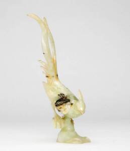 A Chinese pale green stone carving of a pheasant perched on a rock, Republic Period, the stone with paler and darker inclusions, 24.5cm high