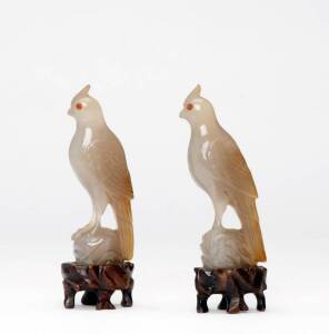 A small pair of Chinese agate birds, early 20th century, each one perched on a rock with inlaid eyes, wood stand, 10.3cm high (not including stand)