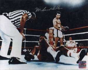 MUHAMMAD ALI, signed colour photograph of Ali standing over George Foreman, size 25x20cm.