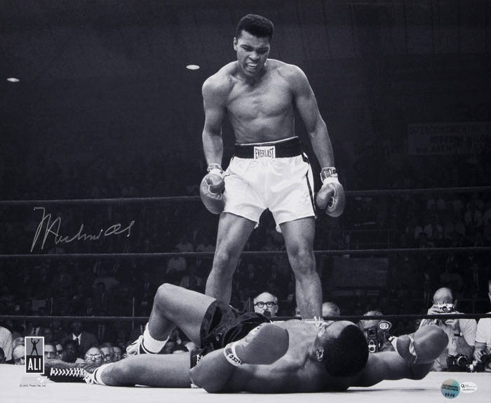 MUHAMMAD ALI, signed b/w photograph of Ali standing over Sonny Liston, size 51x41cm. With 'Online Authentics' No.9646.