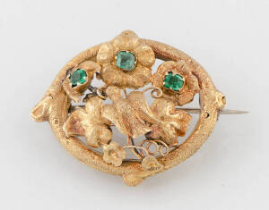 A gold foliate brooch, circa 1870, set with three greenstones, length 3.5cm, width 4cm.