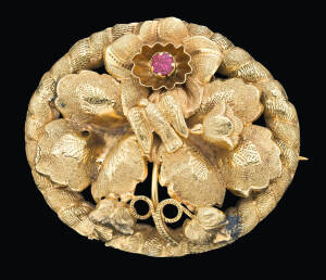 A gold foliate brooch, circa 1870, set with red paste, length 4.8cm, width 3.7cm.