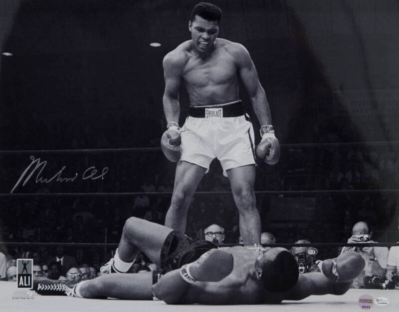 MUHAMMAD ALI, signed b/w photograph of Ali standing over Sonny Liston, size 51x41cm. With 'Online Authentics' No.OA-8090304.