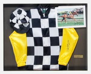 1996 MELBOURNE CUP - SAINTLY: Display with Darren Beadman signatures on replica silks, cap & photograph (framed, 113x93cm); plus print "Phar Lap - The Flemington Onslaught - 1930" (framed, 78x102cm).