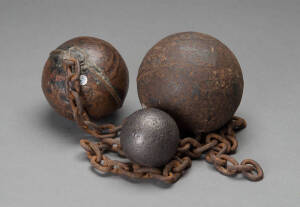 Two convict ball and chains and a lead cannon ball, the largest 13cm diameter