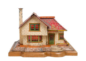 Early tin plate cottage toy mounted on wooden base, early 20th Century. Base 41 x 31cm.