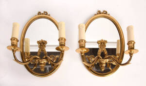 A pair of gilt bronze mounted oval mirror candle sconces, French, circa 1940. 36cm high, 20cm wide.