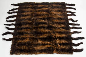 Possum skin bed spread. 33 pelts with tail fringe and satin backing, early 20th century. 135cm by 185cm.